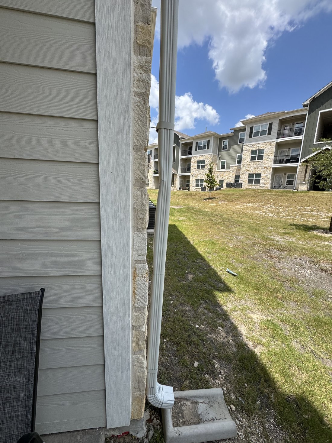 Damaged commercial downspout detached from the wall anchor before repair