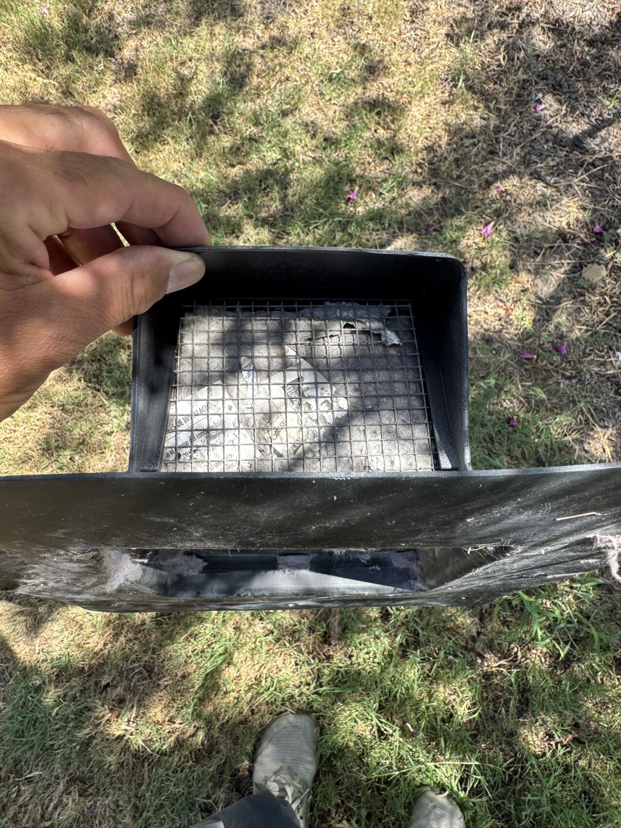 Plastic dryer vent held open showing mesh clogged with lint