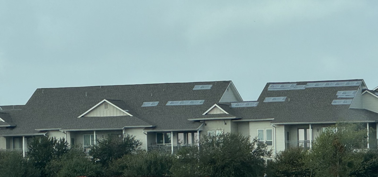 Blue emergency tarps on a multifamily roof after storm damage